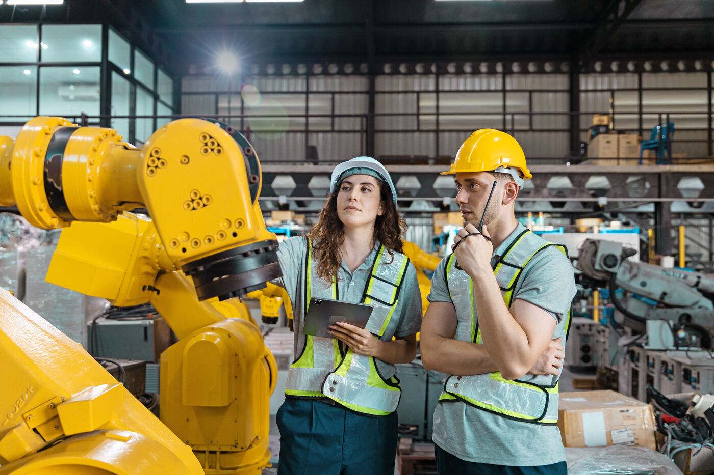 Deux apprentis en tenue de sécurité devant un robot industriel