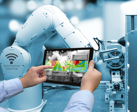 Mains tenant une tablette pilotant un bras robotisé